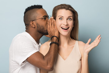 Black man telling secret to stunned surprised woman. - obrazy, fototapety, plakaty