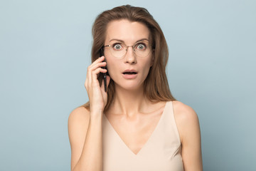 Shocked young woman talking on phone, hearing unexpected news