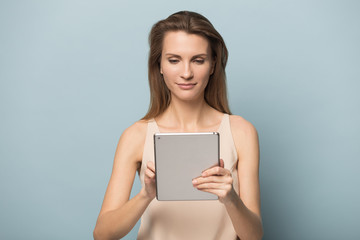 Fototapeta premium Confident young woman using tablet computer, reading book, chatting