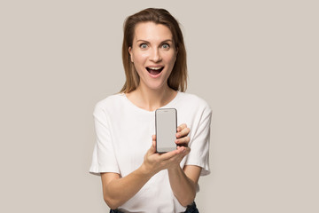 Naklejka premium Happy excited young woman demonstrate new mobile phone model