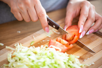 Obraz premium cooking, food and concept of veganism, vigor and healthy eating - close up of female hand cutting vegetables for salad