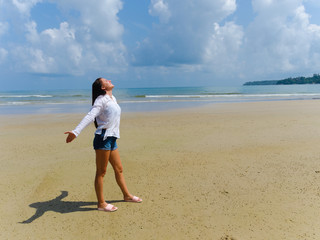 Tanned, carefree and happy young brunette woman on the beach, rejoices in good weather and gentle sun