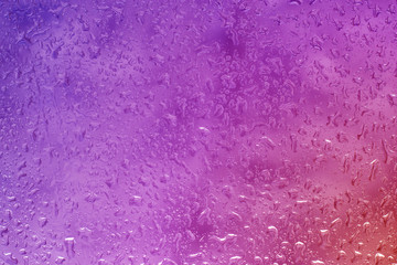 Drops of water on the glass, rain and wet window. The background is pink.