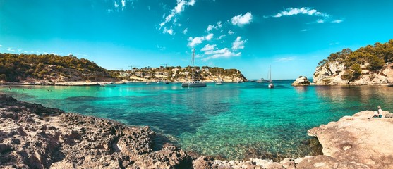 Panorama view of a beach bay with turquoise blue water and sailing boats and yachts at anchor with...