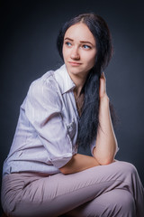Very attractive brunette girl in light trousers and shirt over dark background