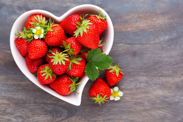 Strawberry heart. Fresh strawberries in plate on white wooden table. Top view, copy space.