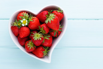 Strawberry heart. Fresh strawberries in plate on white wooden table. Top view, copy space.