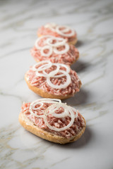 Deutsche Mettbrötchen mit rohen Schweine Mett, Brötchen, Butter, Zwiebeln, Pfeffer und Mett auf Marmor Arbeitsplatte in Küche