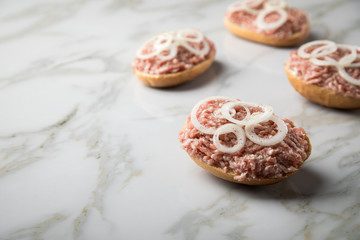 Deutsche Mettbrötchen mit rohen Schweine Mett, Brötchen, Butter, Zwiebeln, Pfeffer und Mett auf Marmor Arbeitsplatte in Küche