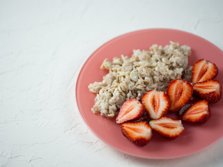 Healthy and tasty summer Breakfast. Oatmeal with strawberries in a pink plate