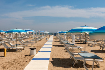 Striped sun umbrellas, sun beds, beach, Rimini, Italy.