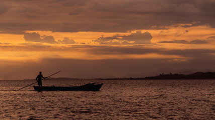 silhouette of fisherman on beach at sunset