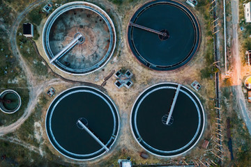 Sewage treatment plant, aerial top view from drone in evening. Industrial wastewater cleaning in round storages