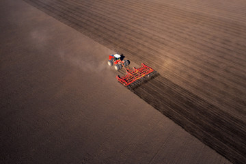 Agricultural industrial tractor plows soil field for sowing , aerial top view. Land cultivation,...