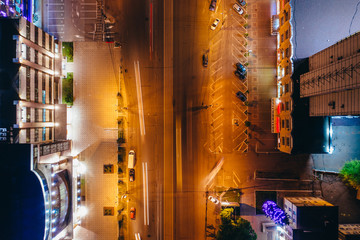 Top view of illuminated city road with car traffic and modern buildings, aerial drone photo