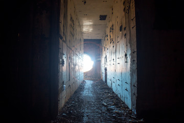 Fototapeta na wymiar Creepy corridor in abandoned nuclear power plant with light from round hole