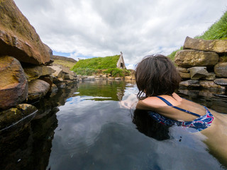Woman bathing in a small hot pool in Hrunalaug, Iceland