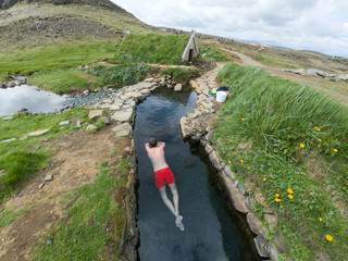Man relaxing in a hot pool in Hrunalaug, Iceland