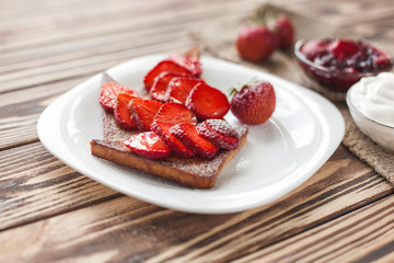 Morning breakfast. Toasts with strawberry and jam. Bread and confiture. Fresh hot toasts with cream. Delicious homemade dessert.
