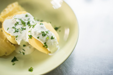 Delicious jacket potatoes. Cooked in water..Nice simple dish with sour cream. Everything on a green plate garnished with herbs.