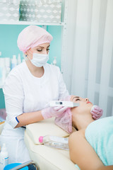 Ultrasonic cleaning of the face. Modern equipment. Cosmetic procedure. Young girl.