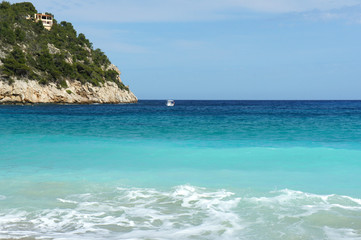 Naklejka premium Small boat near the steep shore. Ibiza Island Bay of San Vicente. Spain.