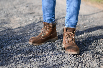 traveler in old hiking yellow boots standing on mountain road with stones