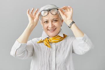 Beautiful fashionable Caucasian woman pensioner with farsightedness taking off her eyeglasses to...