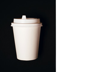One paper cup for coffee or tea on black background. Copy space for text.