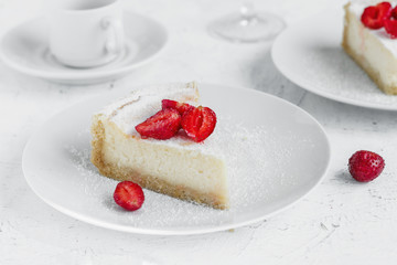 Cheesecake decorated with strawberries on a white plate