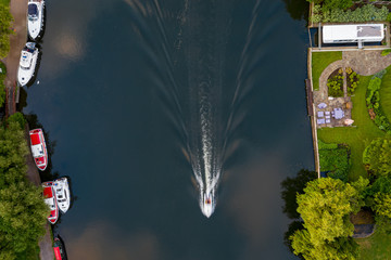 Overhead view of a deliberately speed blurred motorboat on the river Thames at Marlow in Buckinghamshire; the other boats and scenery are all in crisp focus