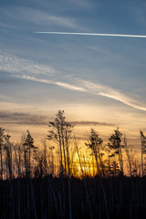 dramatic dark red clouds in sunset over countryside fields and forests