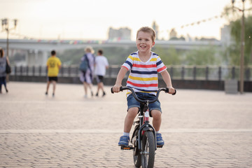 Little boy riding bicycle on the road around the house in the park 