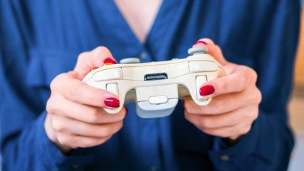Close up shot of woman gamer hand playing video games with joystick or gamepad at home. Gaming, hobby, addiction, video game and leisure time concept © zyabich