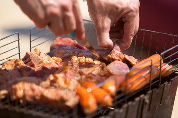 man cooks delicious meat and sausages on the grill outdoors