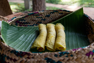 Obraz premium Sweet pancakes served on a banana leaf in a knitted basket. Sri Lankan breakfast.