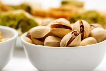 Pistachio in ceramic bowl with traditional oriental sweets in the background, close-up