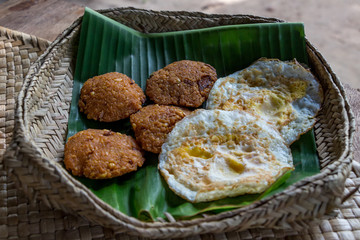 Crispy deep fired vadai snack and omelet on a banana leaf in a knitted basket. Sri Lankan breakfast.