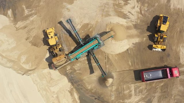Aerial view loading bulldozer in open air quarry. Sand mining industry. Bulldozer machine. Crawler bulldozer moving at sand mine. Mining machinery working at sand quarry. Drone view of mining equipmen
