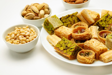Traditional oriental sweets in white plate with different nuts on a white table, side view