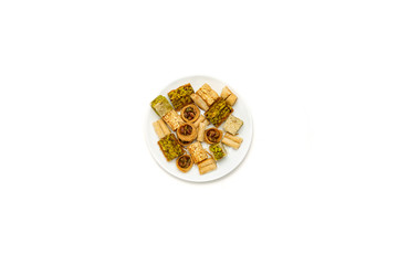Traditional oriental sweets in white plate with different nuts on a white table, top view