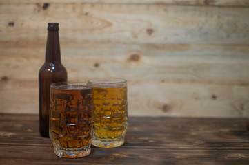 two beer mugs and a bottle on a wooden background