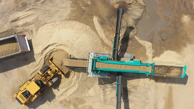 Aerial view loading bulldozer in open air quarry. Sand mining industry. Bulldozer machine. Crawler bulldozer moving at sand mine. Mining machinery working at sand quarry. Drone view