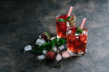 Fresh summer strawberry lemonade with basil and ice on a dark background copy space.