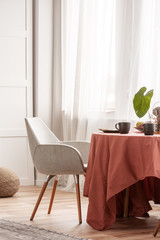 Stylish grey chairs at dining table covered with long tablecloth