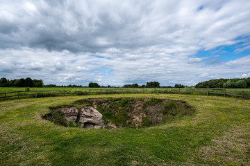 Fototapeta na wymiar archeological pit cave in the ground in meadow