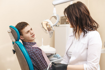 Photo of young female dentist and young male patient in the dentist room