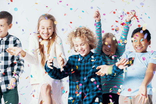 Smiling boy and girl having fun with confetti during birthday party with friends