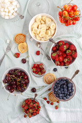 Summer berries strawberries, blueberries, sweet cherries in vases on the table. Top view