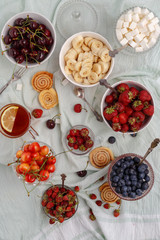Summer berries strawberries, blueberries, sweet cherries in vases on the table. Top view